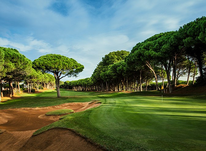 Bunkered green on the 3rd hole framed by pine trees at Golf de Pals